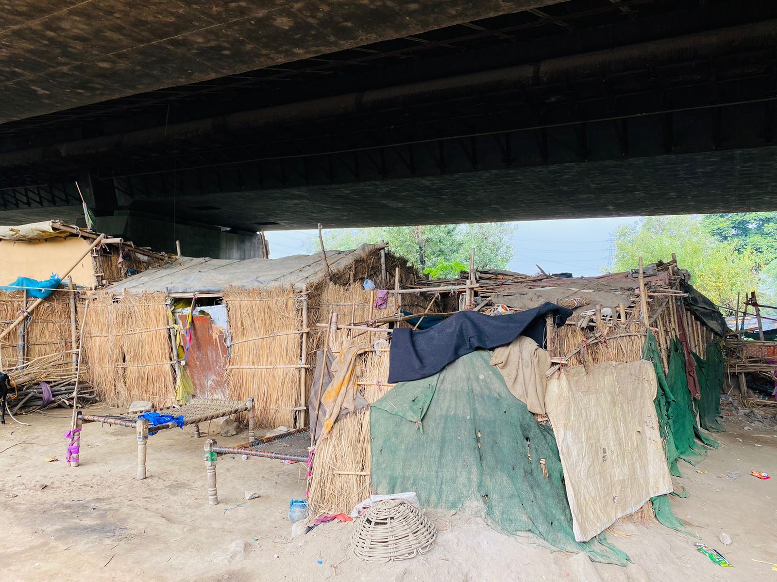 A settlement of thatch homes under a flyover